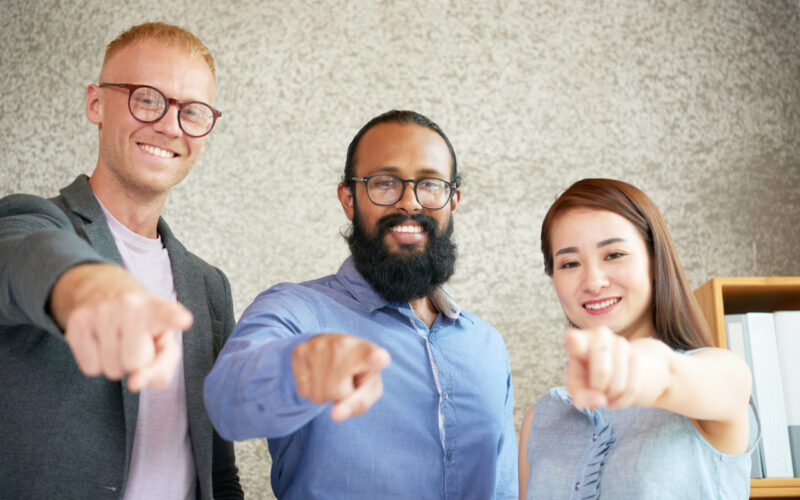Portrait of successful young business team pointing at camera and smiling